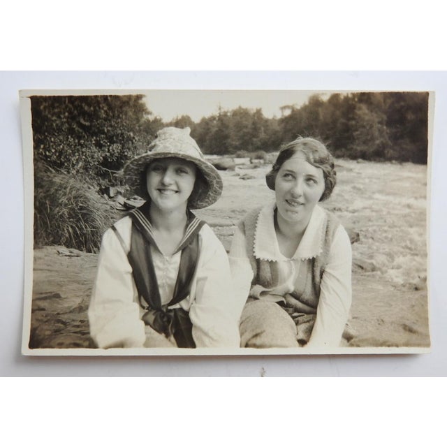 Early 20th century snapshot photograph of two smiling young women by a river. Unframed.