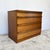 Teak-veneered carcase construction raised on a plinth base. Four full-width graduated drawers with sculptural solid...