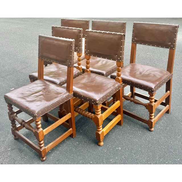 Set of 6 early 1900’s English Cromwellian dining chairs. Crafted in oak with original brown leather and brass tack design....