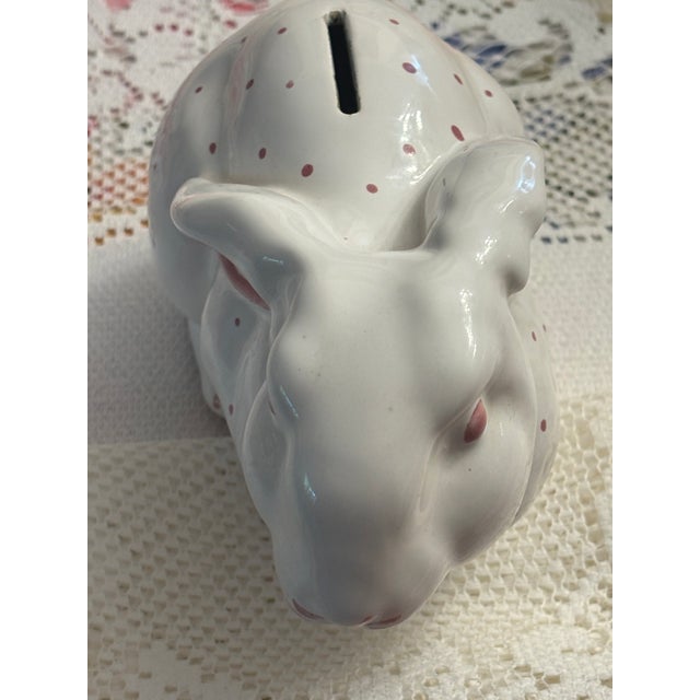 A charming Tiffany & Co. Austria ceramic bunny bank, circa mid-20th century. Finished in glossy white with pink polka...