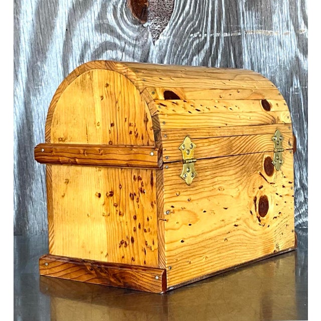 This handcrafted wooden chest features a rounded lid and visible knots, celebrating the natural beauty of the wood grain...