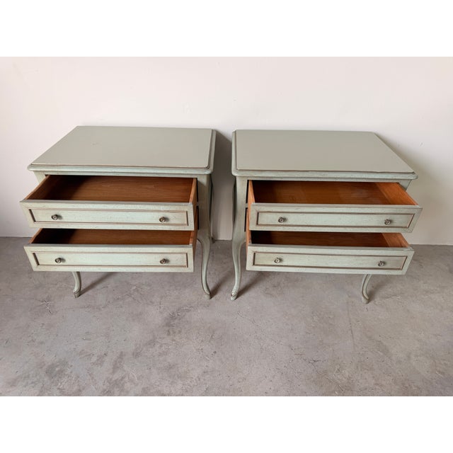 Elegant vintage French Provincial Louis XV style nightstands featuring graceful cabriole legs, two spacious drawers, and a...