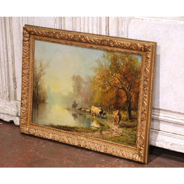 This antique oil on canvas painting by Théodore Levigne (1848–1912) captures a tranquil riverside scene at sunrise, as a...