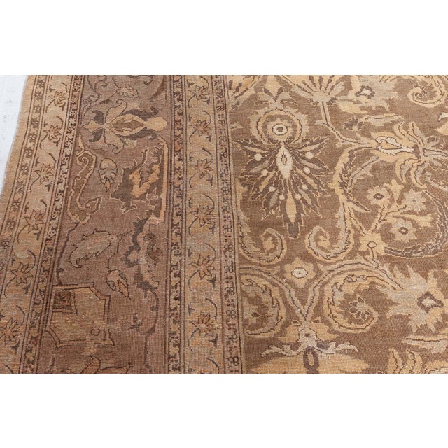 An early 20th century Indian Amritsar antique rug displays traditional botanic design. The brown field with sophisticated...