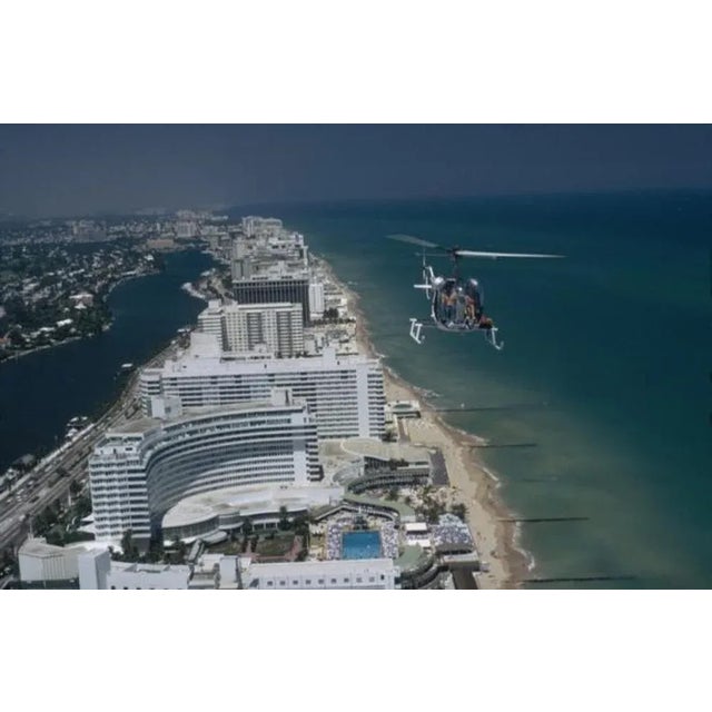 Aerial Miami Beach 1972 by Slim Aarons Slim Aarons Limited Estate Edition A helicopter carrying tourists hovers over the...