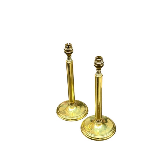 English lamps, circa 1950, made of polished gilt brass. Featuring a smooth cylindrical column with a wide, slightly...