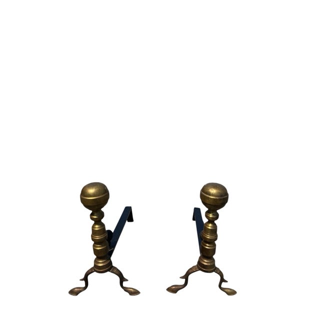 Matching pair of antique brass fireplace andirons with large ball finials, turned columns, tripod feet, and iron log...