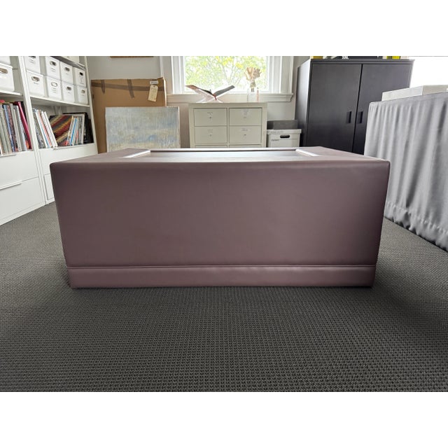 Brand new custom ottoman in a deep mauve leather, with hidden wheels, custom-built by a high end workroom in New Jersey....