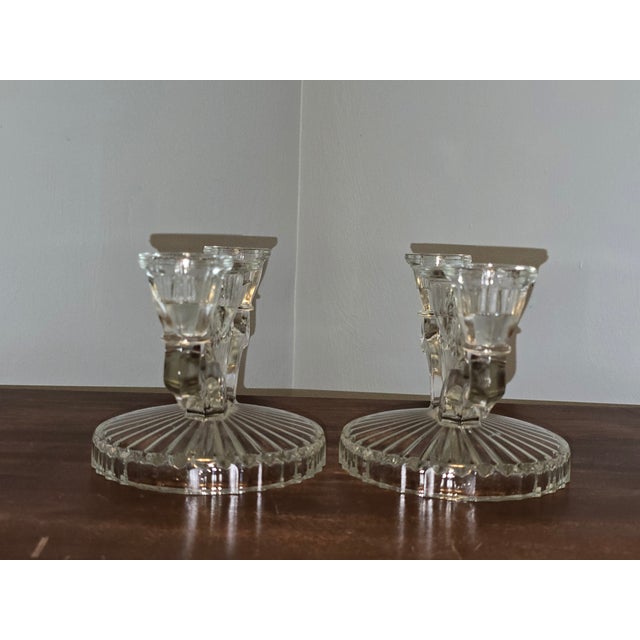 A charming pair of vintage pressed‑glass double‑arm candleholders, featuring elegant scrollwork, a central fan‑inspired...