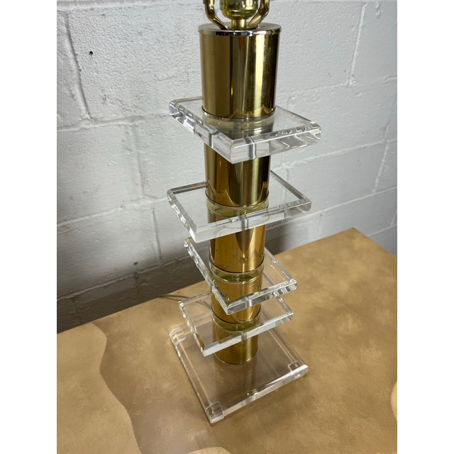 Striking vintage table lamp featuring a polished brass column accented by graduated clear Lucite platforms. Its tall,...