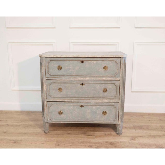 A refined Swedish Gustavian-style chest of drawers. Crafted in pine, this piece is painted in a soft blue tone, a color...