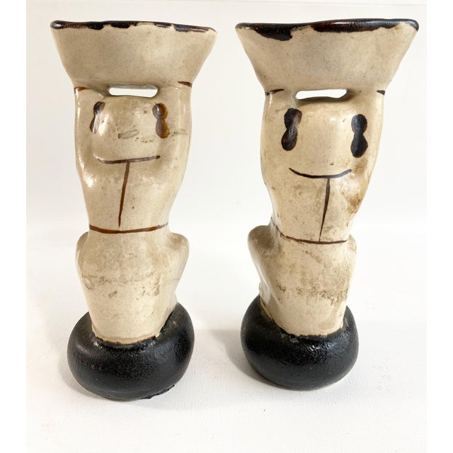 Two cherubic children crouch in offering — a pair of Cizhou-style figural holders bearing the bat emblem of good fortune.