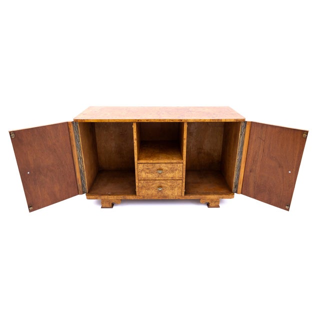 An elegant Art Deco-style sideboard, manufactured in Poland in the 1950s. The piece is crafted from high-quality veneer...