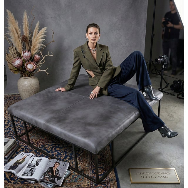 A sculptural leather ottoman designed as a functional coffee table, combining soft upholstery with a structured metal...