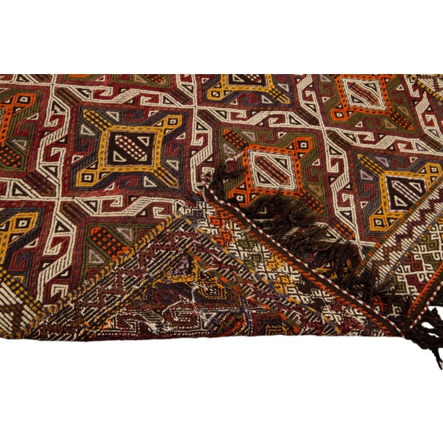 Beautiful vintage Indian Sumack hand-knotted wool rug with a brown field. This piece has a multi-color accent in a...