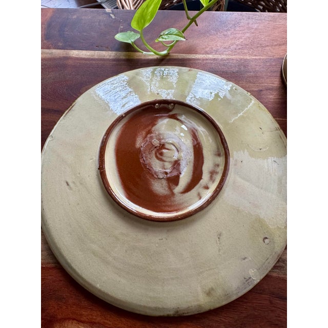 A charming mid-century French ceramic plate featuring a hand-painted fruit motif in warm, earthy glazes—an effortlessly...