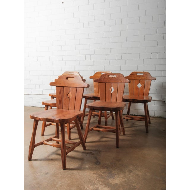 Description: A charming set of six vintage Alpine pine chairs featuring hand-crafted construction and sculptural cut-out...