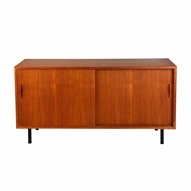 Sleek and perfectly simple - this vintage sideboard features a beautiful warm teak patina, and has two sliding doors which...