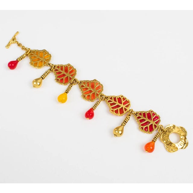 This mesmerizing Kenzo Paris floral link bracelet features carved gilded metal framing with resin leaves and dangling...