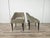 A pair of 1960s-era living room or bedroom armchairs, entirely upholstered in light green fabric and with wooden legs. The...