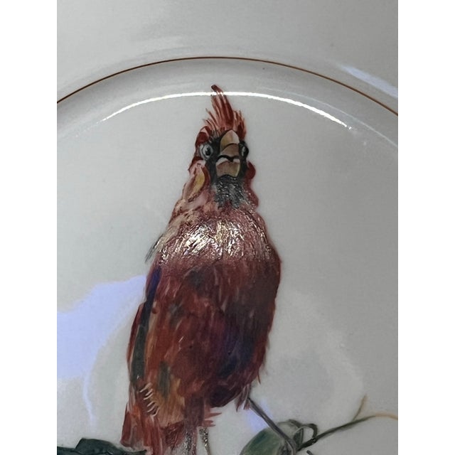 This elegant porcelain plate features a hand-painted cardinal perched among flowering branches, rendered in warm,...