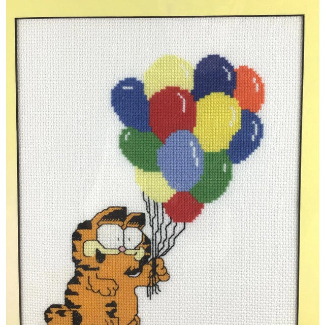 Fun and quirky Garfield the Cat holding a bunch of colorful balloons. This piece was hand crafted by intricate needle...