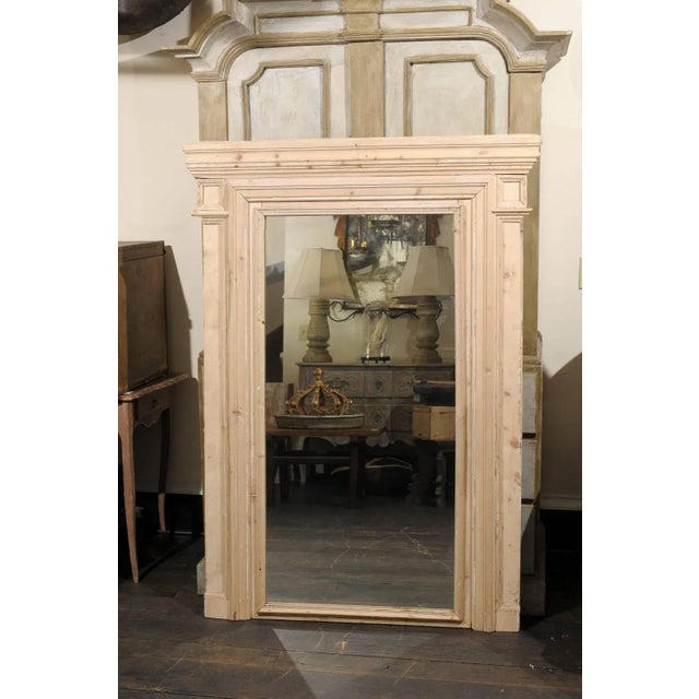 A French 19th century trumeau mirror with clean simple lines. This large French mirror features a natural wood finish with...