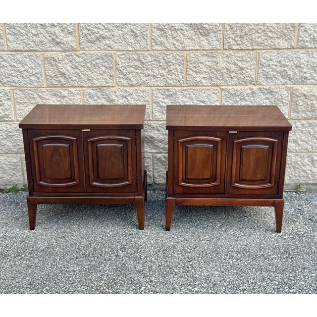 Pair of mid-century walnut nightstands with a rectilinear case set on tapered legs. Each cabinet features two front doors.