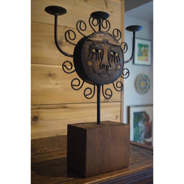 An unusual wrought iron candelabra which features a mustachioed sun on one side and a subdued moon on the other. The...