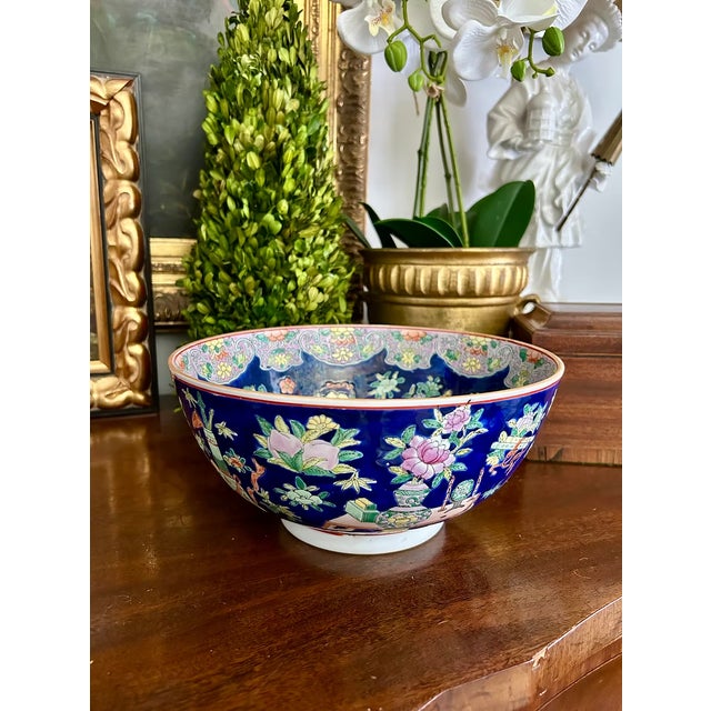Chinese porcelain bowl decorated in the famille rose palette with a deep cobalt-blue ground, featuring finely painted...