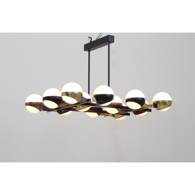 Monumental Stilnovo chandelier from the 1950s with 12 glass and metal globes. Made with 12 opaline glass globes, brass,...