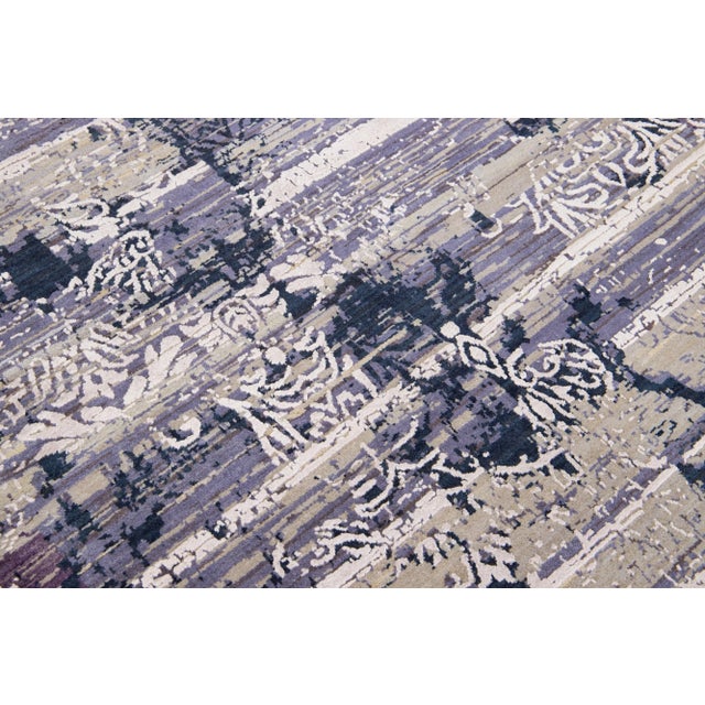 Constructed with a durable blend of Tibetan and Indian wool and silk, this light gray and beige rug boasts an intricate...