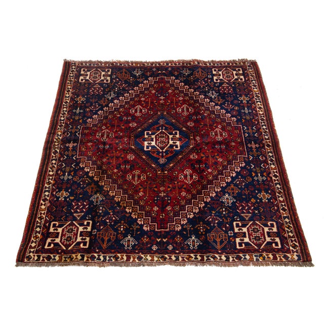 This hand-knotted vintage Persian Shiraz features a red and blue field throughout the geometric design, complemented by...