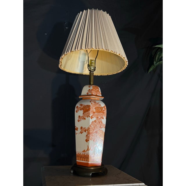 Elegant vintage porcelain table lamp featuring a detailed floral and botanical design in warm terracotta tones over a...
