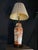 Elegant vintage porcelain table lamp featuring a detailed floral and botanical design in warm terracotta tones over a...