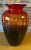 This large art glass vase is a masterpiece of hand-blown craftsmanship, skillfully blending shades of red, orange, and...