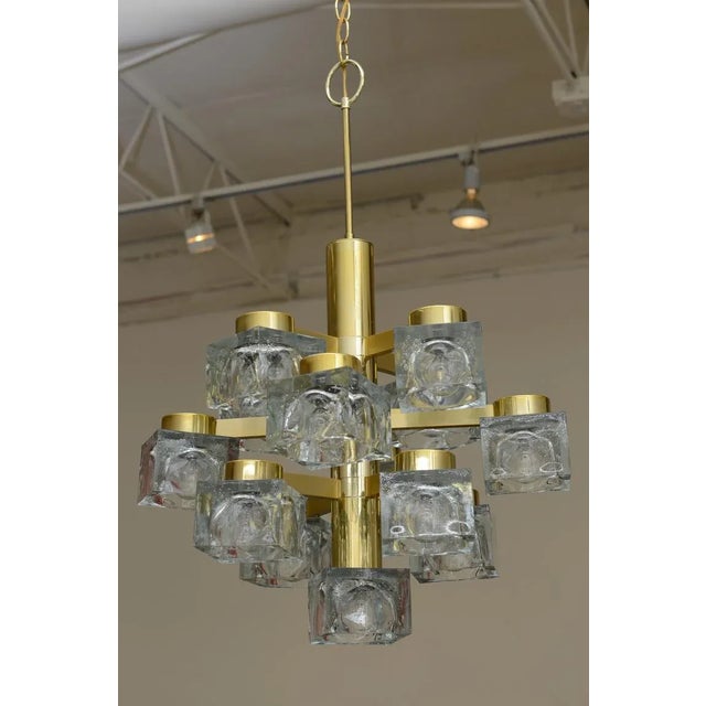This chandelier by Italian Gaetano Sciolari has 13 cube glass lights suspended from a sculptural brass arm attached to a...