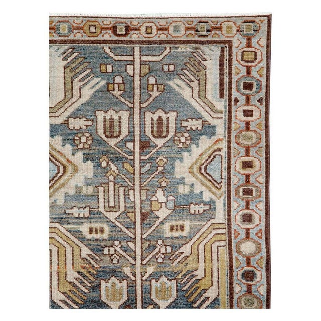 This mid-20th-century Persian Malayer rug presents a distinctive allover geometric-floral design across a muted blue...