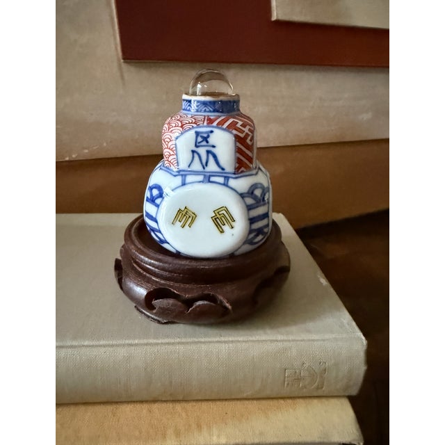 This charming miniature porcelain vessel features hand-decorated blue, red, and white motifs accented by a central...
