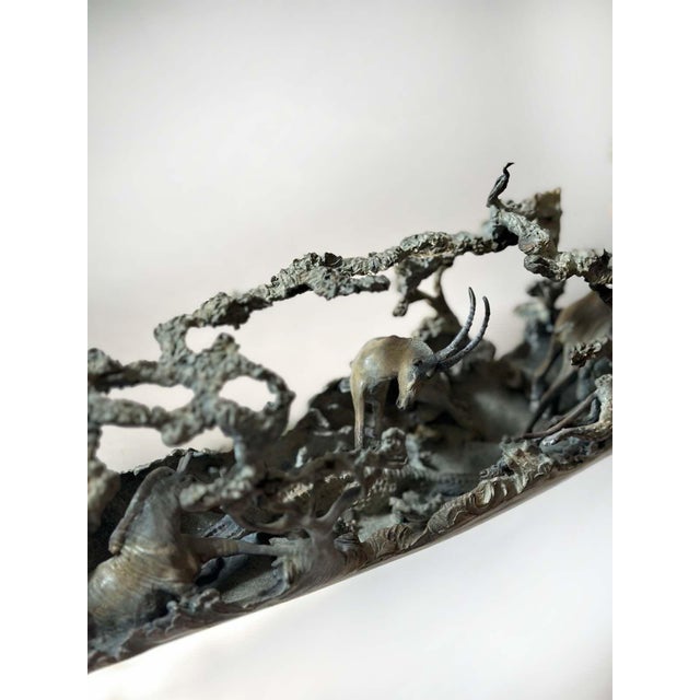 Astonishing cast bronze sculpture that emulates a mammoth tusk, adorned with a captivating parade of African animals and...