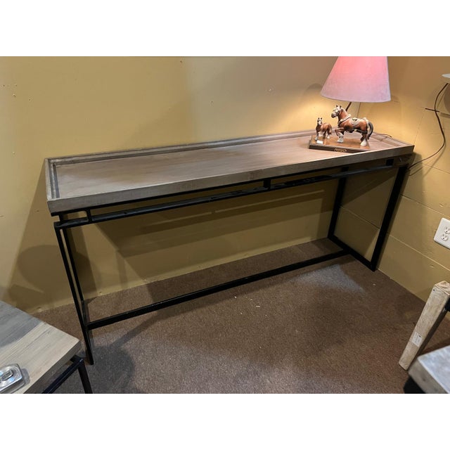 This striking long console table featuring a warm wood top set on a bold geometric metal base. The clean lines and...