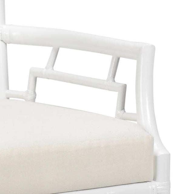 White finish on rattan fretwork armchair with attached off white fabric cushion. 38h x 21w x 19d