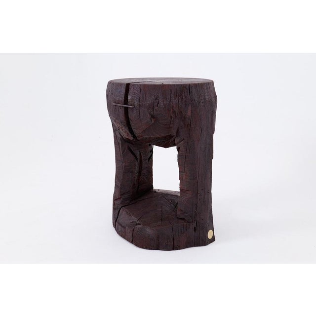 This monolithic side table is a one-of-a-kind piece, hand-carved from a single, substantial hardwood log. Its powerful...