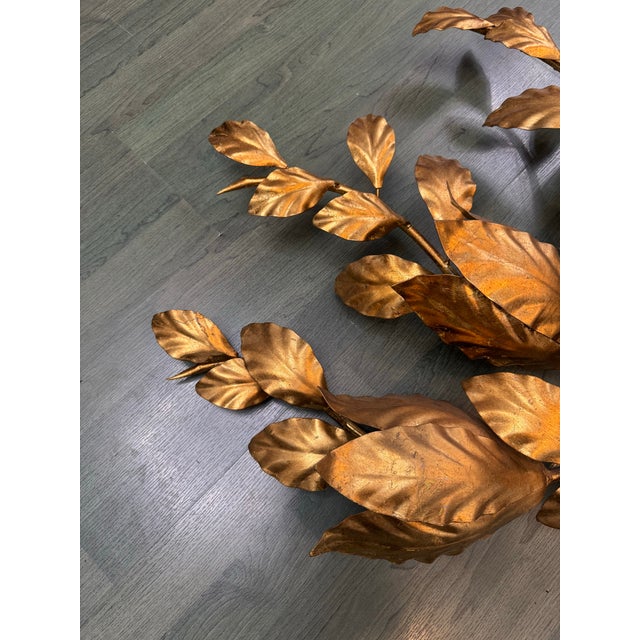 Dramatic and sculptural wall-mounted lamp featuring an expansive botanical design crafted from brass-colored aluminum....