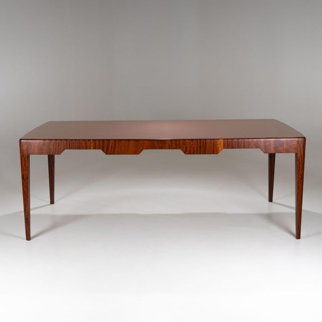 Exceptional dining table featuring a rectangular top and tapered legs. The apron is distinctively shaped with trapezoidal...
