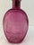 Pretty glass decanter in deep pink featuring an Americana raised design on both sides of bottle with cork lined stopper....
