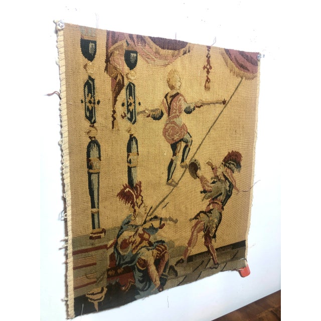 Hand woven 100% wool tapestry fragment featuring two musicians and a tight rope walker in muted blue, red and oatmeal...