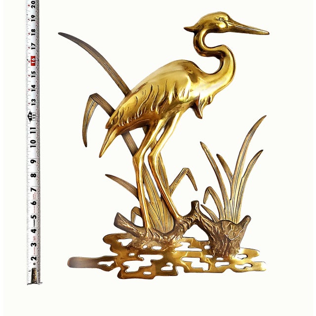 Offering a vintage solid brass wall sculpture depicting an egret perched upon a tree branch standing in a marshland, circa...