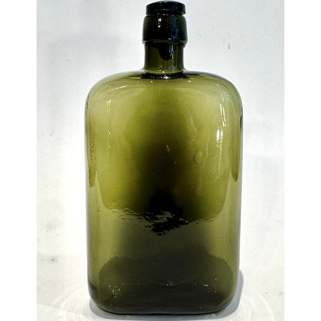 A handsome vintage olive green glass apothecary bottle retaining its original dark glass stopper with cork. The bottle's...