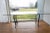 A long, thick glass top rectangular dining table with a beveled-edge, rounded corners and a weathered wrought iron base....